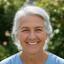 Bennie Upenieks, retired nurse with silver hair, smiling warmly in a Dublin garden